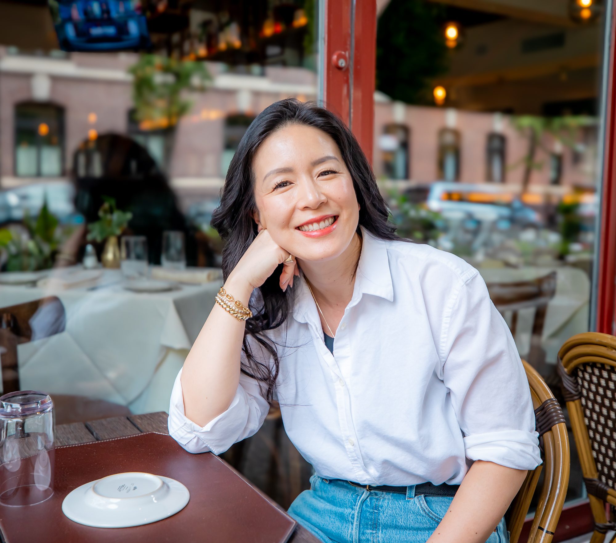 Emma Chao smiling at a sidewalk café table in Brooklyn
